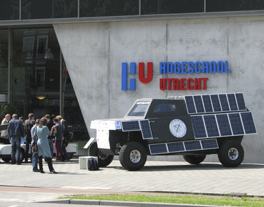 905940 Afbeelding van een kleine vrachtauto vol zonnepanelen, tentoongesteld voor het schoolgebouw van de Hogeschool ...